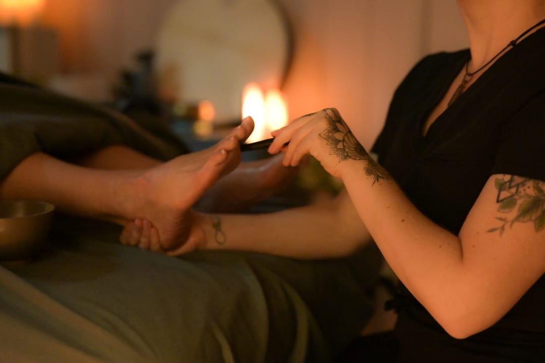 Krysta working a reflex point on a client's foot with a wooden reflexology stick